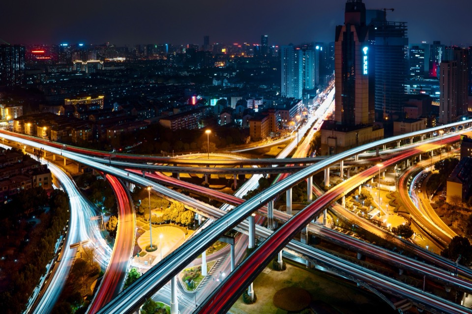 城市夜间立交的航拍，光带自路口向四面延伸